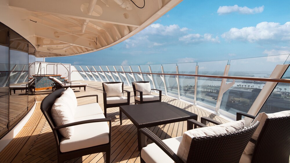 A verandah with an ocean view, lounge chairs, a whirlpool, a table and 4 chairs in a Disney Cruise Line Concierge Royal Suite with Verandah Stateroom 