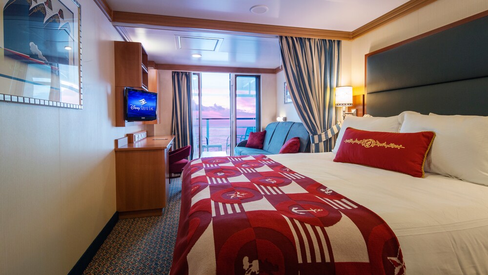 A Disney Cruise Line Deluxe Oceanview with Verandah Stateroom with a desk, storage shelves, a verandah with an ocean view, a sofa and a bed