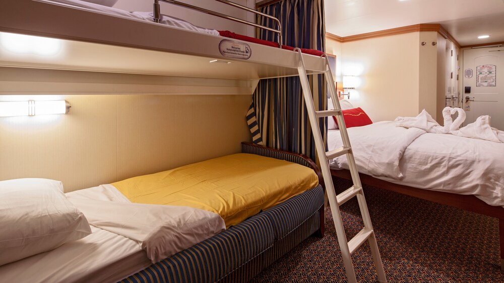 A Disney Cruise Line Deluxe Oceanview with Verandah Stateroom with a sleeper sofa, a bed, storage shelves, a TV and a desk