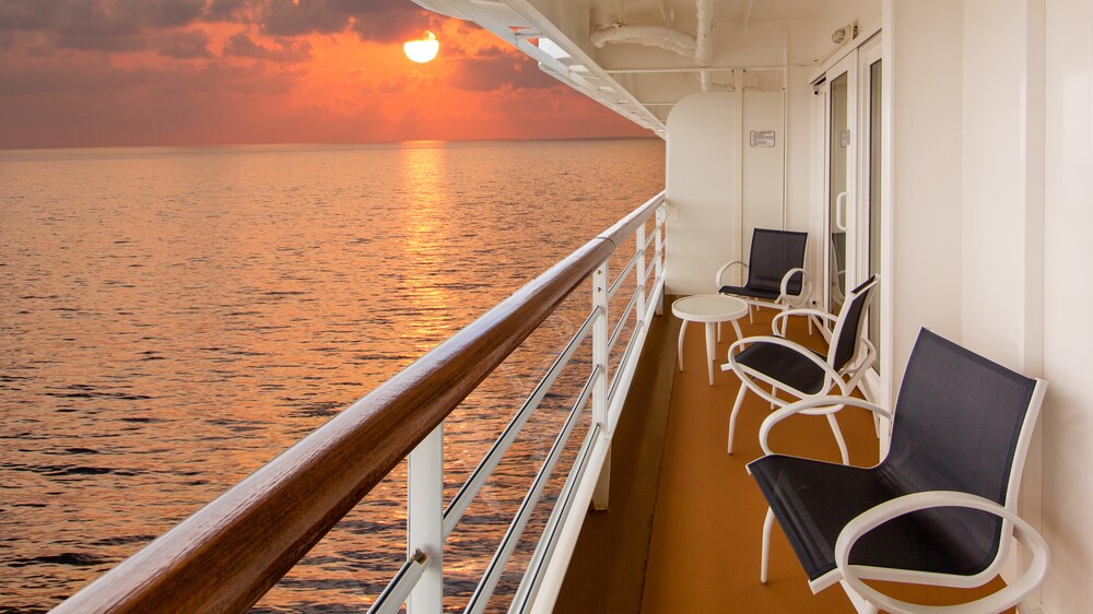 Three chairs and a table in a verandah facing the ocean in a Disney Cruise Line ship