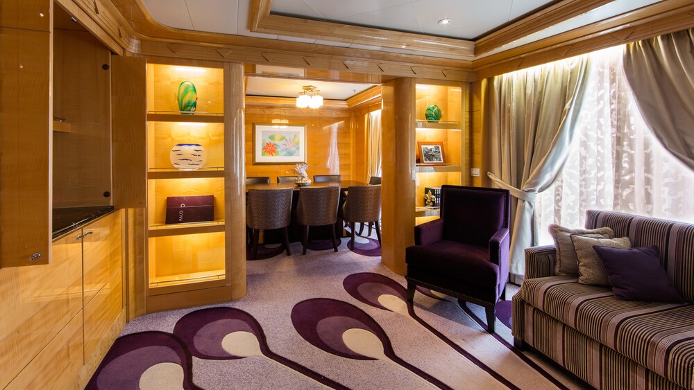 A Disney Cruise Line Concierge Royal Suite with Verandah living room with a sofa, chair and shelves