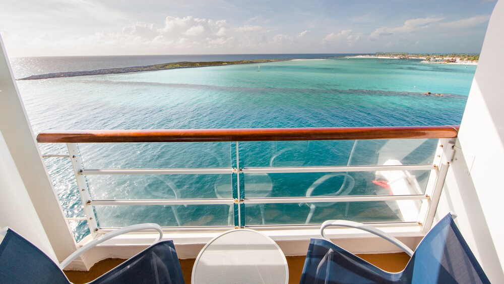 A Disney Cruise Line stateroom verandah facing the ocean with 2 chairs and a table