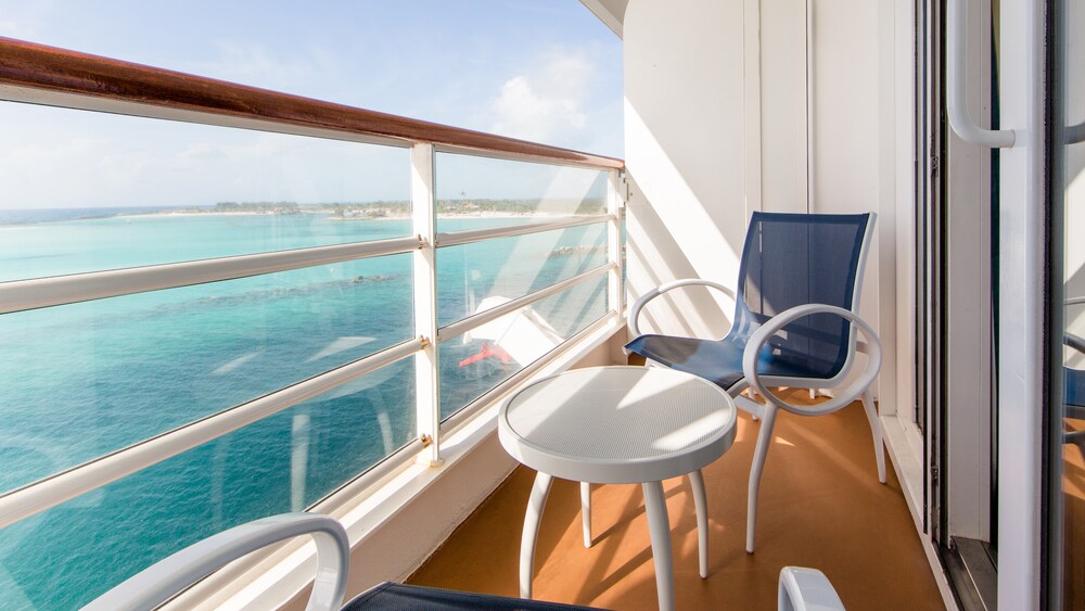A Disney Cruise Line stateroom verandah facing the ocean with 2 chairs and a table
