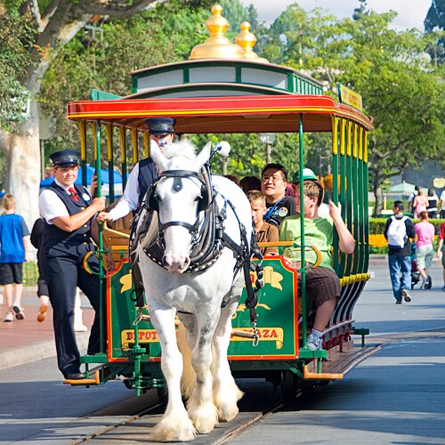 A horse pulls an open streetcar full of Guests down Main Street U.S.A.
