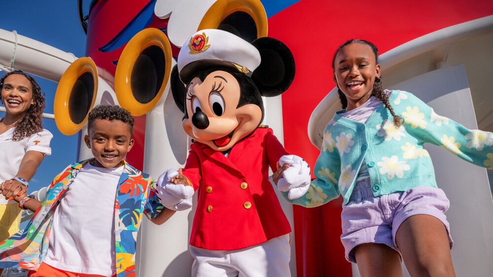 A family holding hands with Captain Minnie Mouse on the deck of a Disney Cruise Line ship