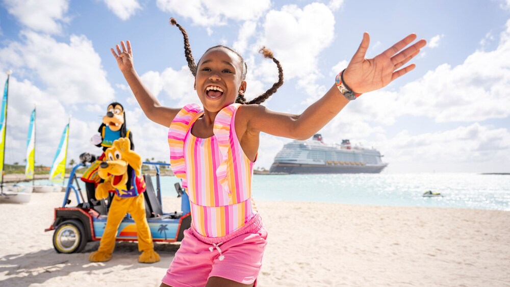 A girl laughing and smiling at the camera with Goofy and Pluto in the background