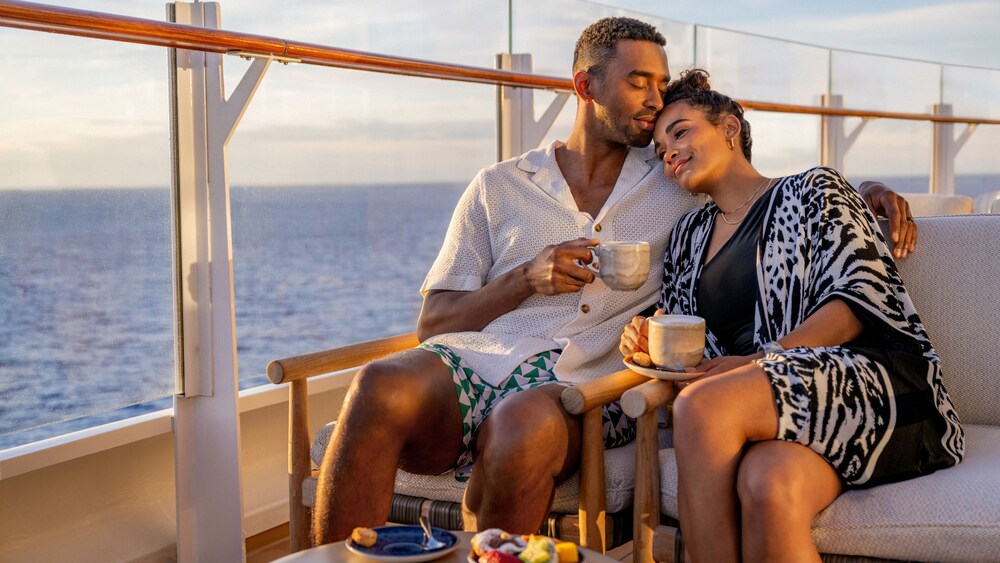 A couple sitting on a boat, each with a cup of coffee