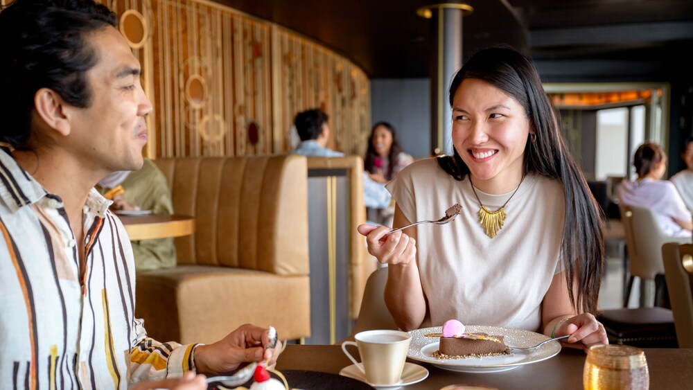 A man and a woman smiling while eating dessert at a dining table