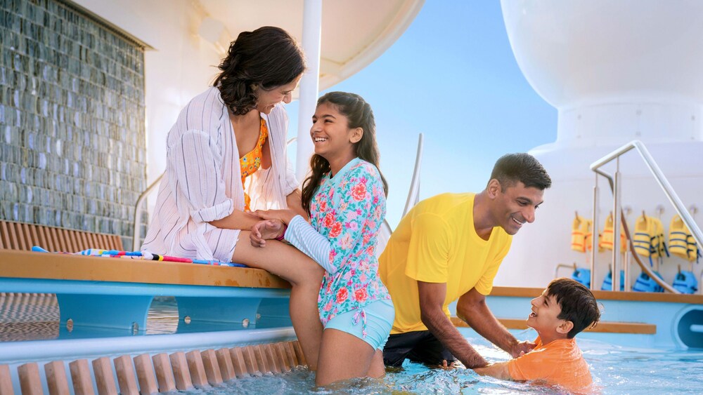 Two parents playing with their 2 children in a pool