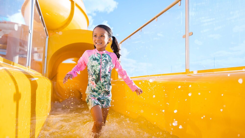 A young girl walking out of a pool at the end of a waterslide