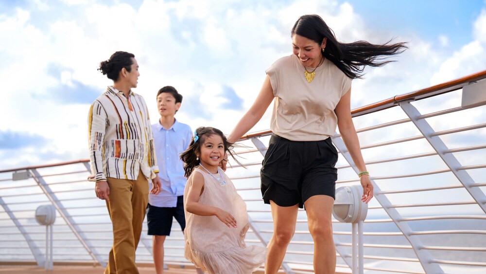 Two parents, a boy and a young girl walking along a cruise ship's upper deck