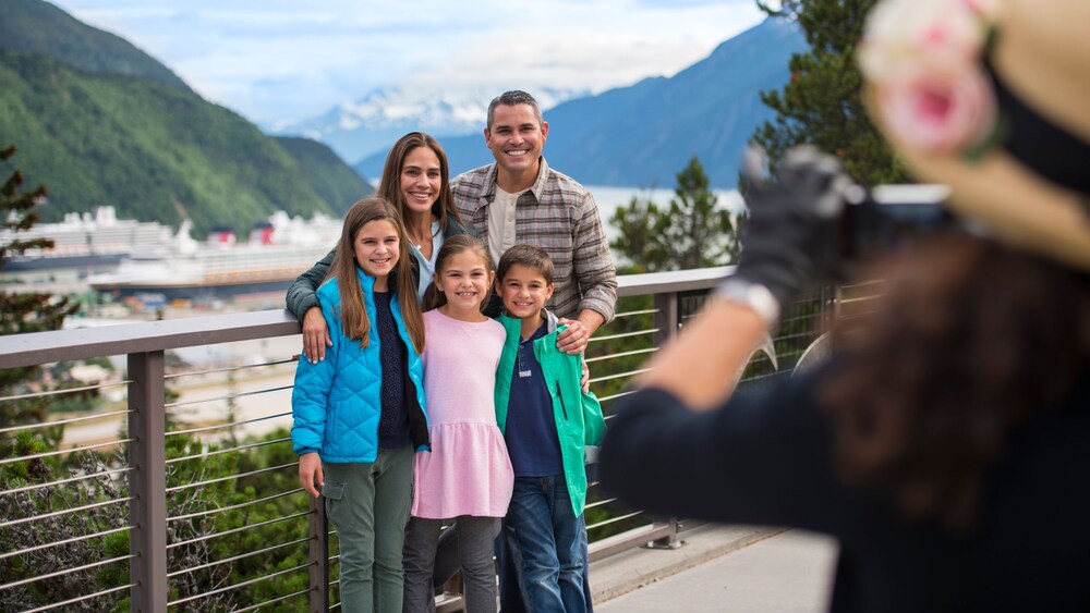 Uma família sorrindo para uma foto em uma ponte em Skagway, Alasca 