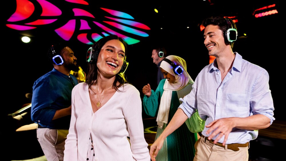 Guests wearing light up headphones and dancing at a disco party with lights overhead