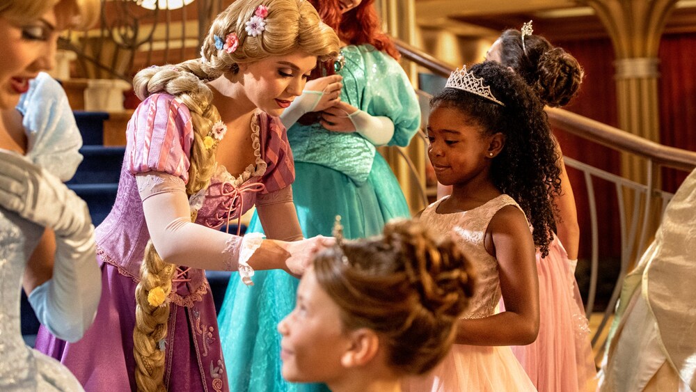 Niñas con looks de princesas de Bibbidi Bobbidi Boutique interactuando con Cenicienta, Rapunzel y Ariel