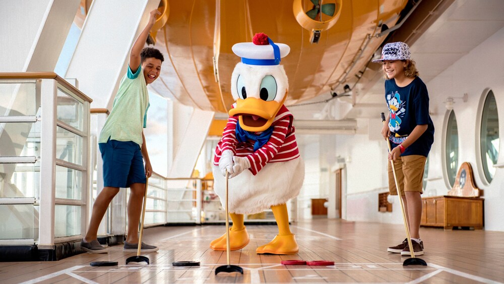 Boys playing shuffleboard with Sailor Donald Duck on the deck of the Disney Dream