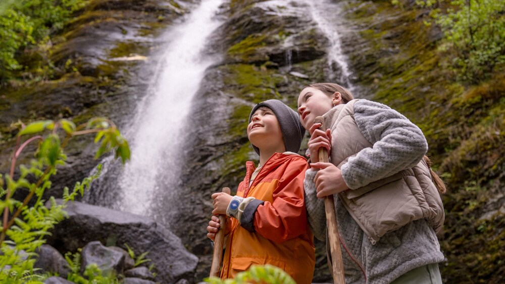 A boy and a girl looking up in awe at a waterfall