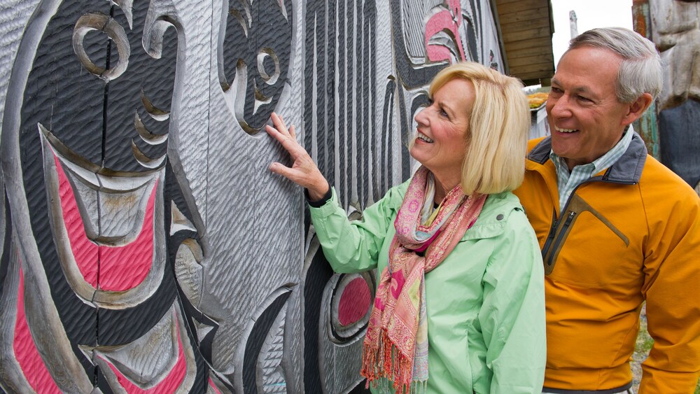 A man and a woman admiring a Clan House in Ketchikan, Alaska