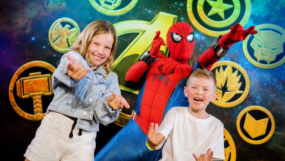 Dos niños posan junto al Hombre Araña, todos haciendo su característico gesto de lanzar telarañas con la mano