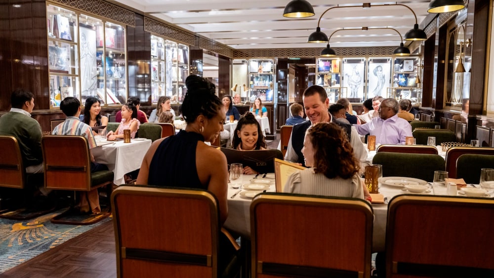 Guests dining in an elegant 1920s themed restaurant with linen table cloths and leather chairs