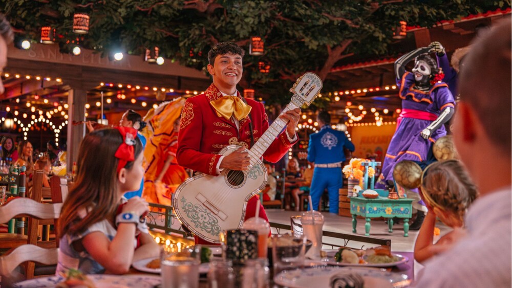 Músicos y bailarines que se presentan en el escenario mientras los Huéspedes cenan en Plaza de Coco en el Disney Treasure