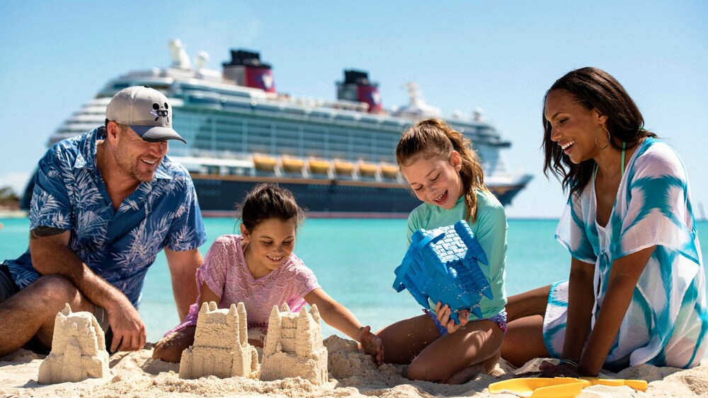 A family of 4 making sandcastles on Castaway Family Beach and a Disney Cruise Line ship docked in the background