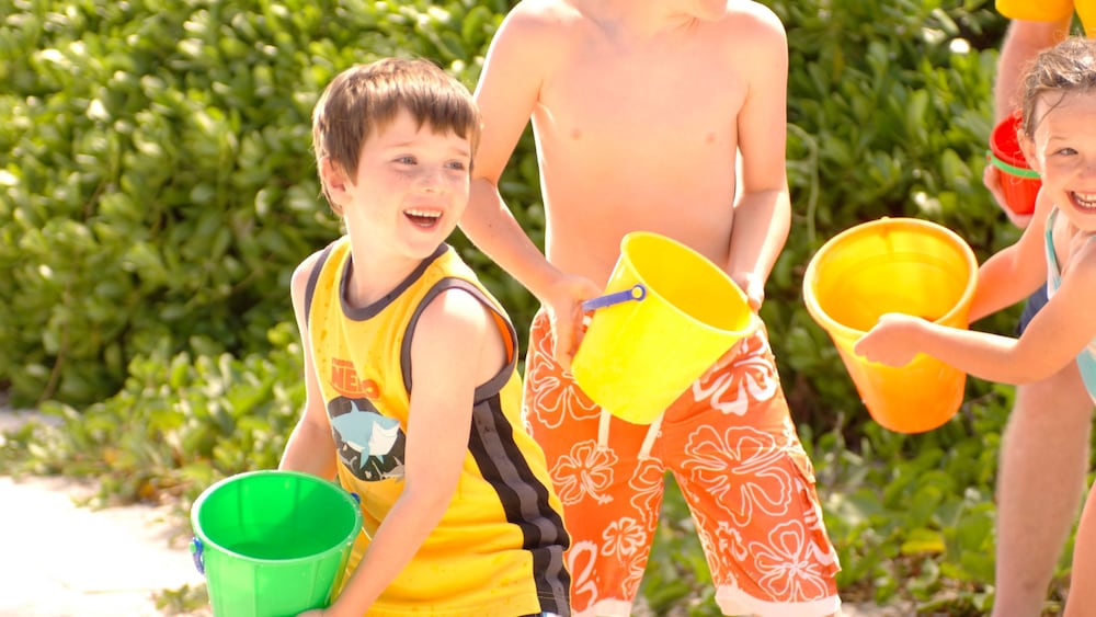A boy splashing in water with a bucket at Scuttle’s Cove on Disney Castaway Cay