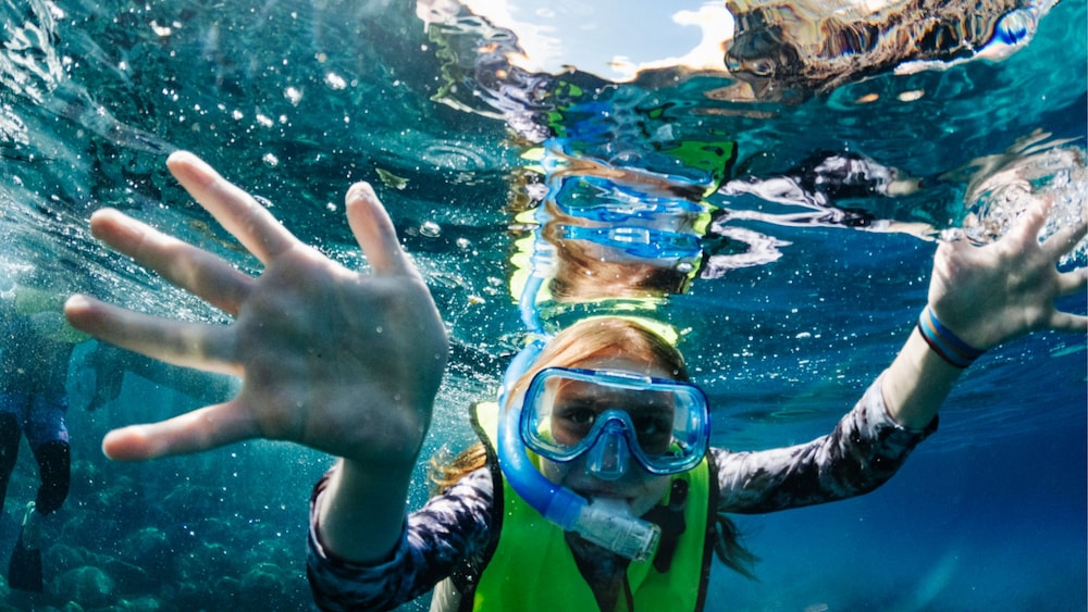 Un niño con gafas mientras practica esnórquel bajo el agua