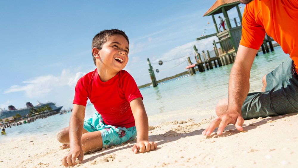 A young Guest and his father playing in the sands of the Disney Castaway Cay beach