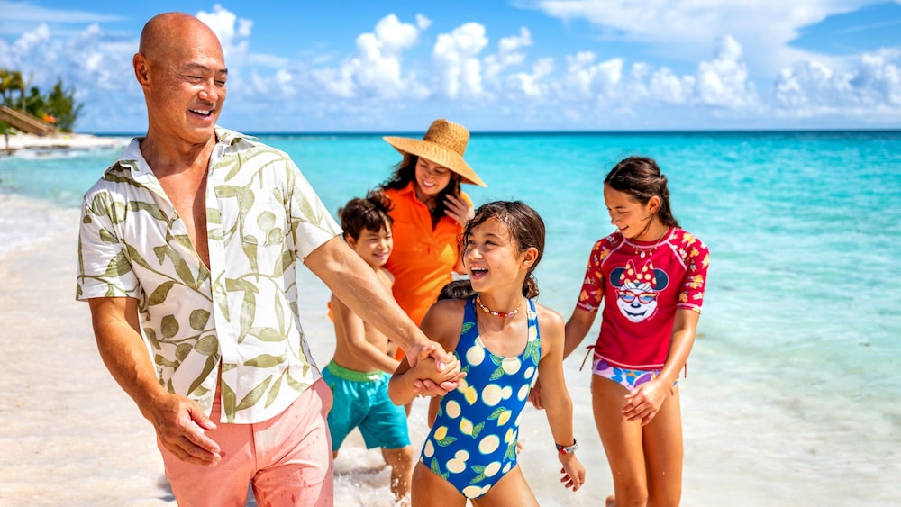 Una familia tomándose las manos mientras caminan por una playa