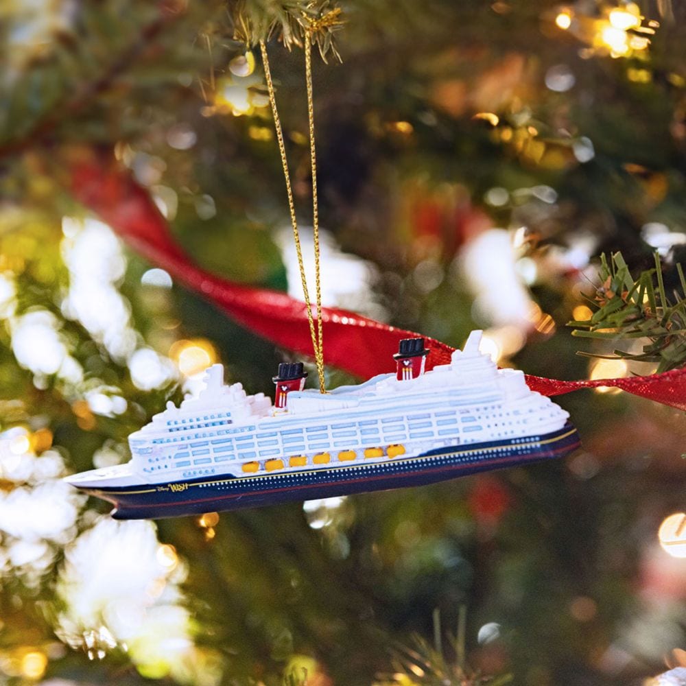 A Disney Cruise Line ship ornament hanging from a lit Christmas tree