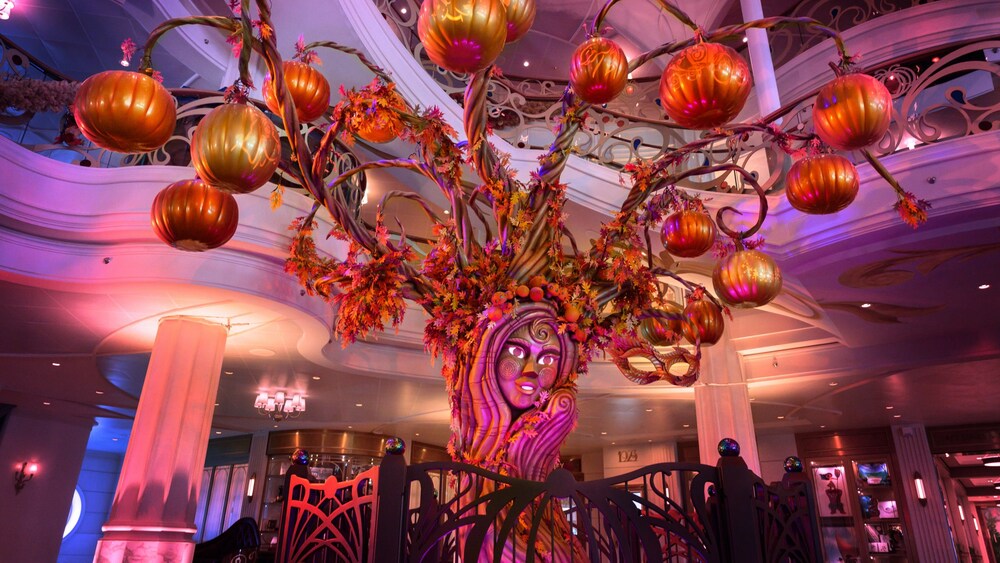A towering Halloween pumpkin tree with a decorative face adorns a Disney cruise line ship atrium