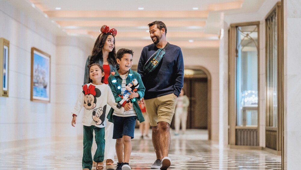 A family of 4 walking together wearing Disney merchandise