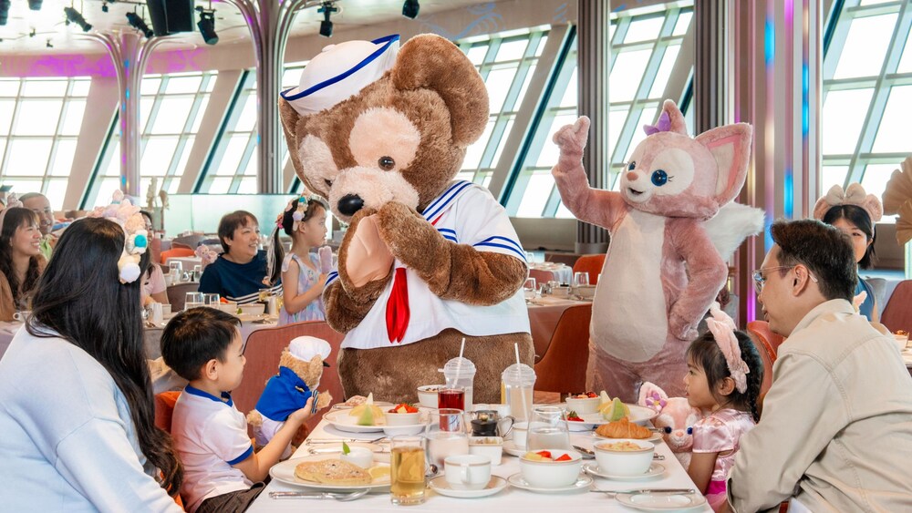 While having breakfast aboard the Disney Adventure, a family with 2 small children enjoys an encounter with Duffy the Disney Bear and his fox friend, LinaBell