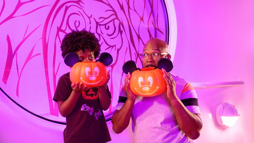 Pai e filho segurando baldes de abóbora do Mickey Mouse