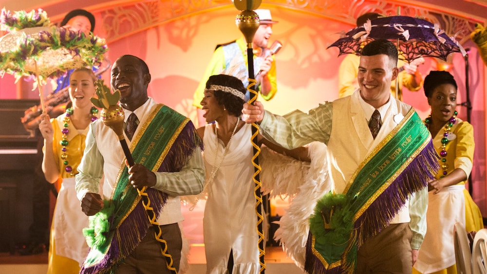Princess Tiana and other costumed performers with props engaged in a New Orleans style celebration 