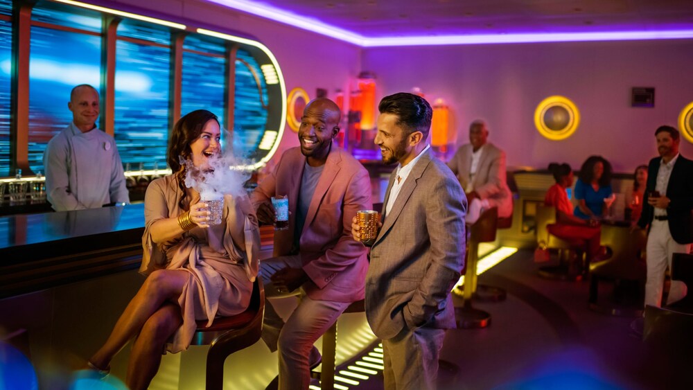 A group of people laugh while drinking cocktails at Star Wars Hyperspace Lounge