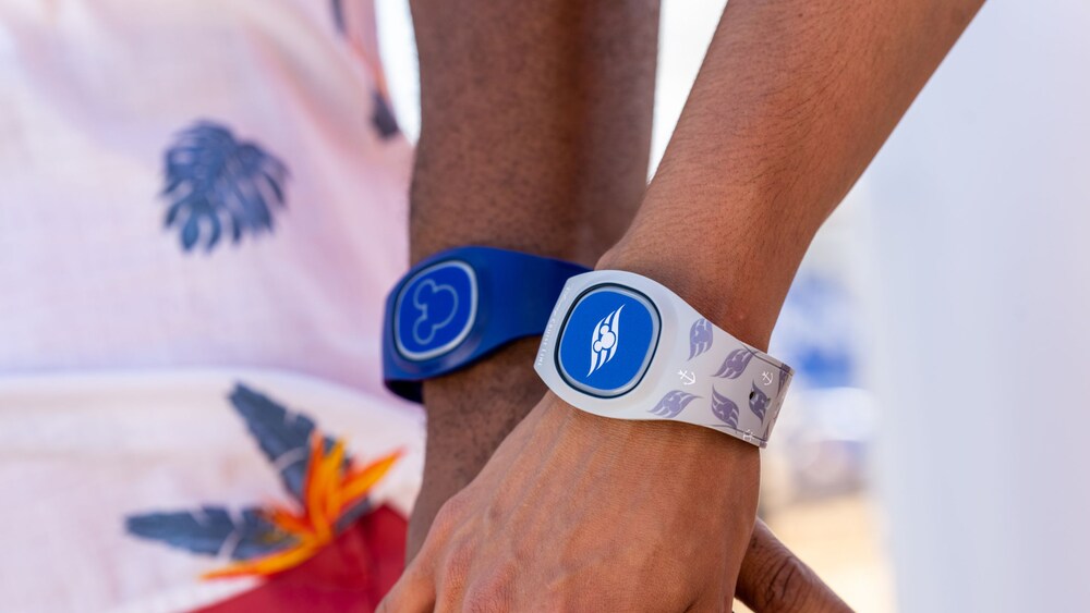 A person's hand holding another's, each wearing a Magic Band