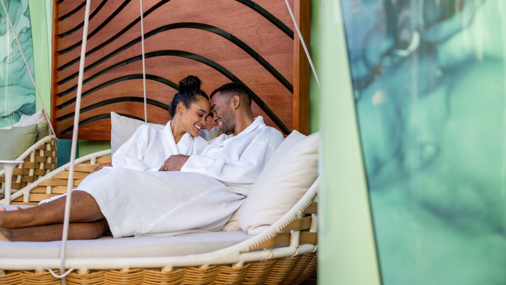A man and a woman embracing in spa robes on an outdoor hanging day bed