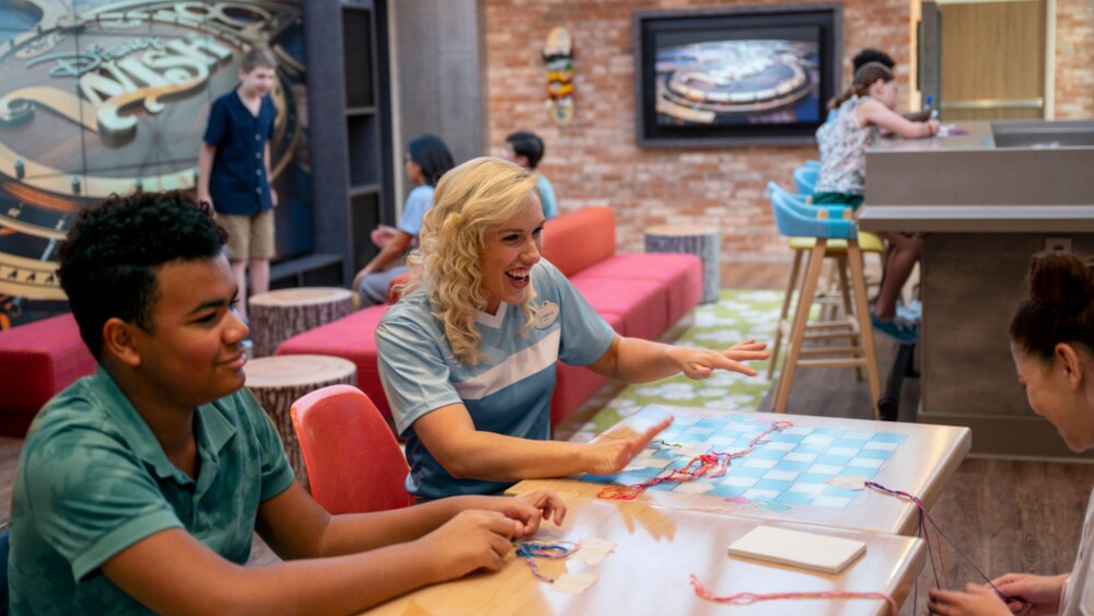 Kids making friendship bracelets with a Cast Member at Edge, a tweens youth club