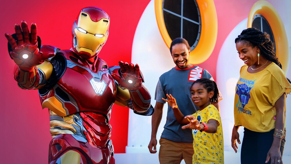 Dos Pasajeros y su hijo posando con Iron Man junto a la chimenea de un crucero Disney