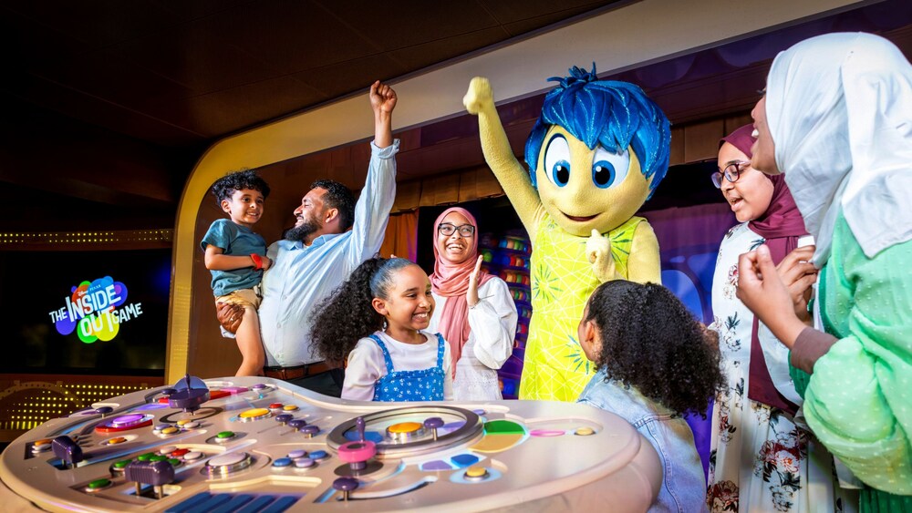 Eine fröhliche Familie spielt The Inside Out Game mit Joy in der Nähe ihrer Steuerkonsole