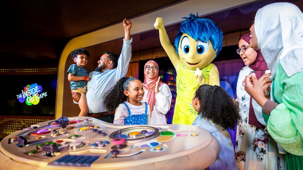 Una familia feliz jugando a The Inside Out Game con Alegría junto a su panel de control