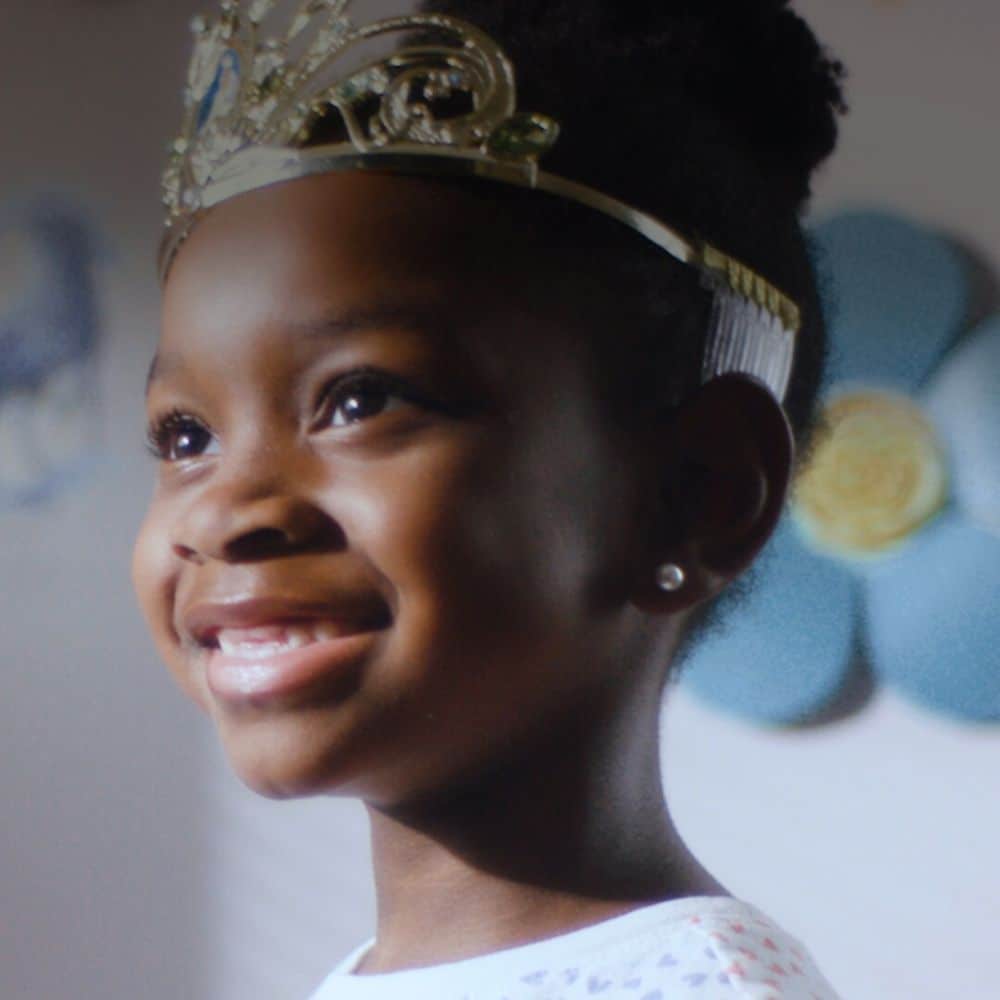 A smiling girl wearing a princess crown
