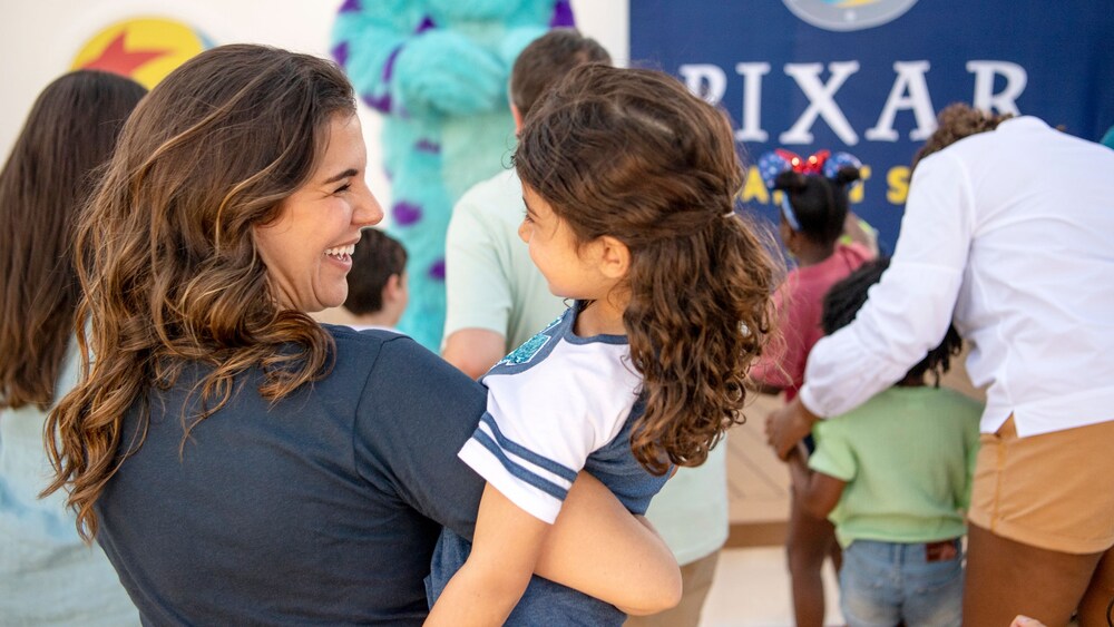 A mother holding her daughter while waiting to meet Sulley from Monsters, Inc.