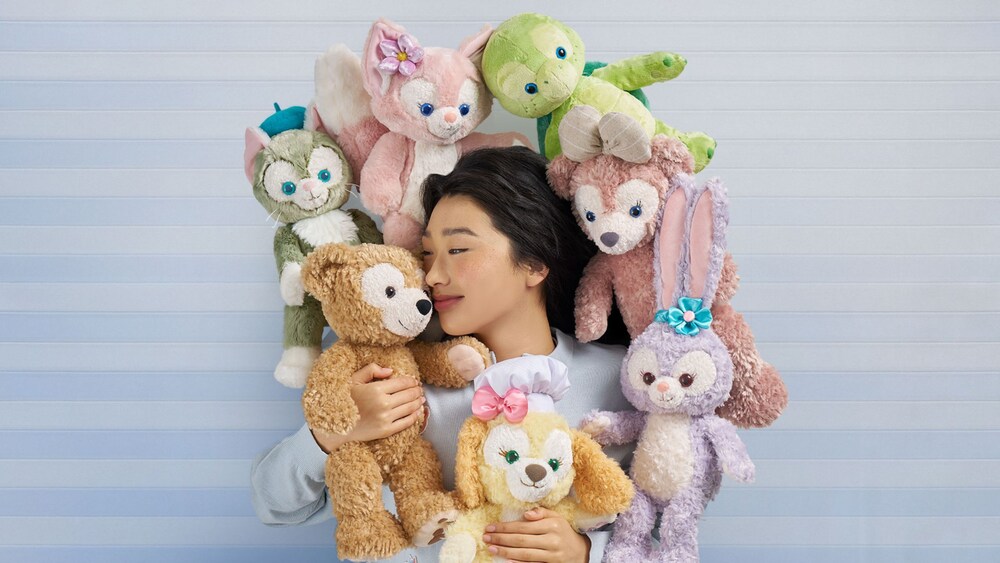 A girl lying down among a group of plushes from Duffy and Friends