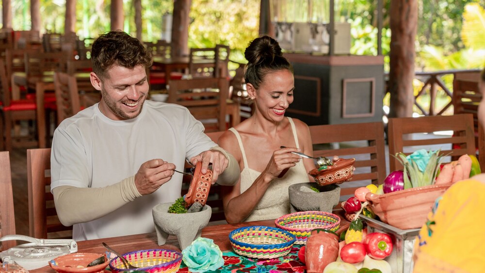 Two Guests sitting at a table and adding ingredients into a molcajete for mixing