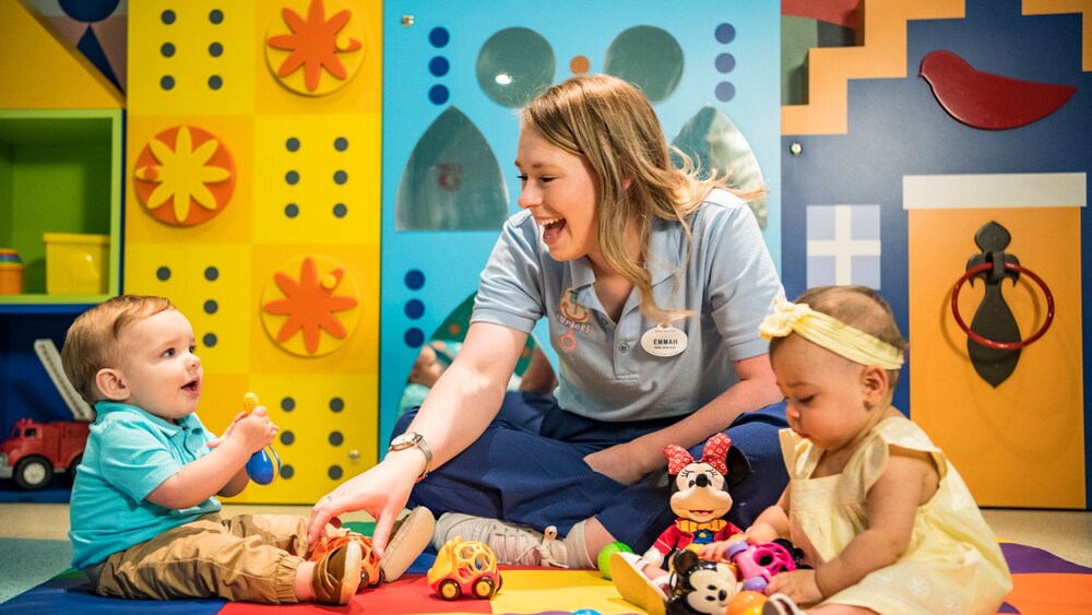 A Cast Member playing with 2 babies inside the ‘it’s a small world’ nursery on board the Disney Adventure