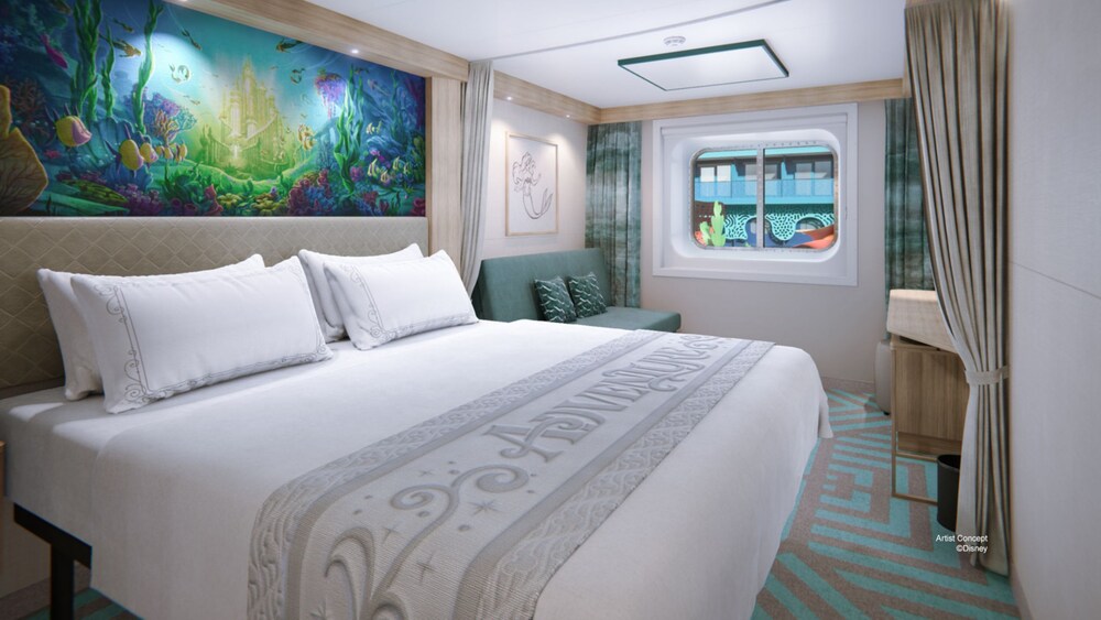 A Deluxe Inside Stateroom with a bed, a sofa, privacy curtains and a window with Disney Discovery Reef views