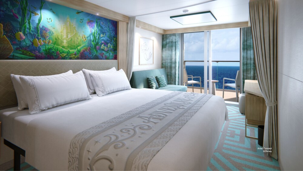 A Deluxe Oceanview Stateroom with a bed, a sofa, Disney artwork on the walls and glass doors that open to a verandah