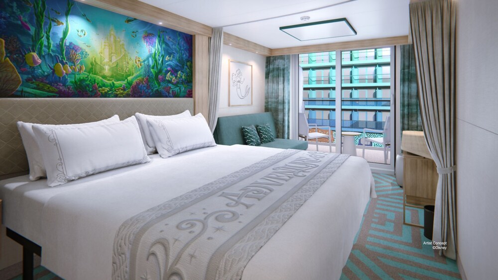 A Deluxe Reef View Stateroom with a bed, a sofa and glass doors that open to a verandah with Disney Discovery Reef views